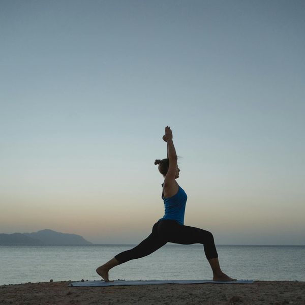 Silhouette of a woman stretching at sunrise, representing renewed energy.